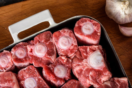Raw pork ribs with onion and garlic on a wooden cutting board.の写真素材