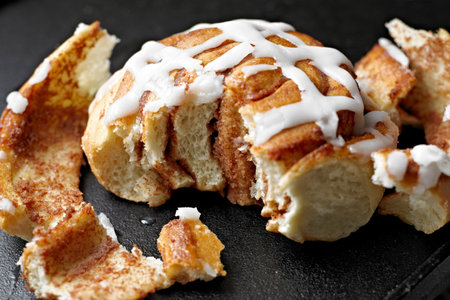 Cinnamon rolls with sugar glaze on a black slate plate.