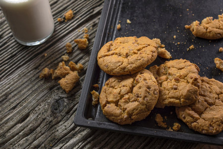Chocolate chip cookies on a black tray with a glass of milkの写真素材
