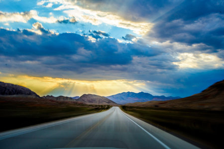 Driving on an empty highway through the high mountains at sunset.の写真素材