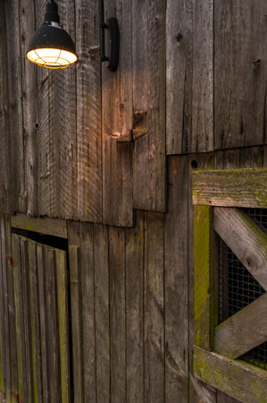 Old wooden door with a lamp in the evening light. Close-up.の写真素材