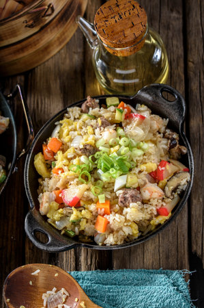 Fried rice with vegetables and meat in a cast-iron panの写真素材