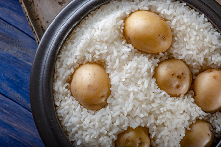 Rice with potatoes in a pot on a wooden background. Selective focus.の写真素材
