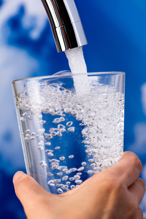 Closeup of a man's hand pouring water into a glass.
