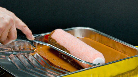 hand of a woman painting a metal tray with a paint roller.の写真素材