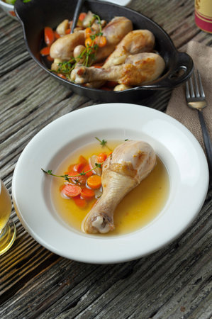 Chicken leg soup with vegetables on a rustic wooden table, top viewの写真素材