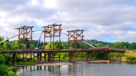 Old rusty metal bridge over the river in the summer on a cloudy dayの写真素材