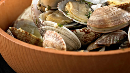Clams in a wooden bowl on a dark background close up