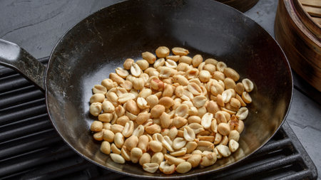 Roasted peanuts in a frying pan on a black stone background.の写真素材