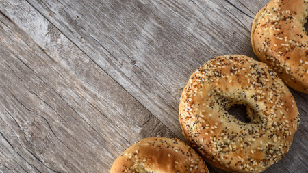 Freshly baked bagels with sesame seeds on rustic wooden backgroundの写真素材