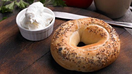 Sesame bagel with cream cheese and parsley on wooden boardの写真素材