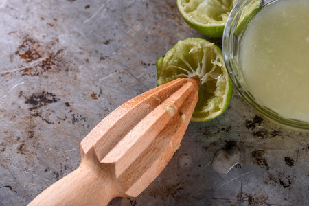 Fresh lime juice in glass and wooden juicer on grunge backgroundの写真素材