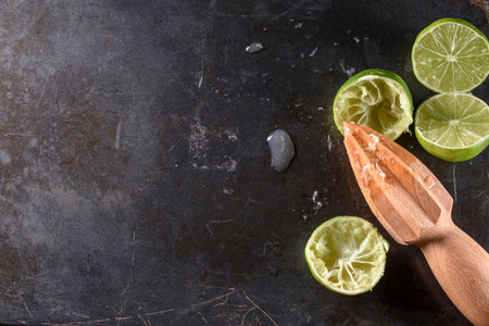 Fresh limes with wooden reamer on black background. Top viewの写真素材