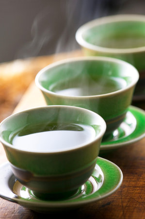Green tea cups with steam on wooden table. Selective focus.の写真素材