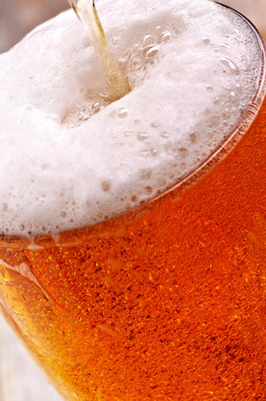 glass of beer with foam on a wooden table, close-upの写真素材