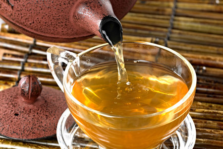 Cup of green tea with teapot on bamboo mat backgroundの写真素材