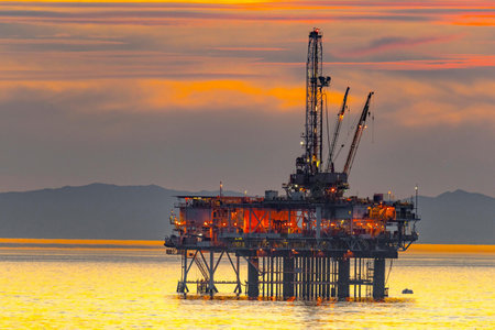 Oil and gas platform in the middle of the sea at sunset.