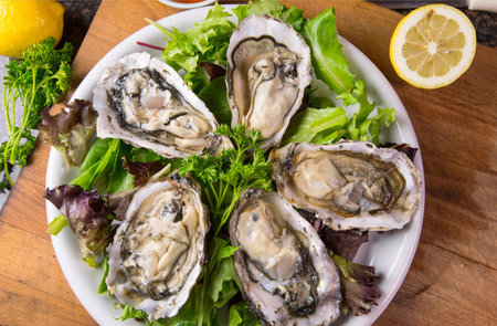 Fresh oysters with lemon and parsley on a white plate.