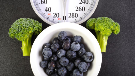 Healthy eating concept. Close up of fresh blueberries, broccoli and scales on black background