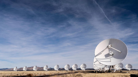 Group of satellite dishes in a field under a blue sky with cloudsの写真素材