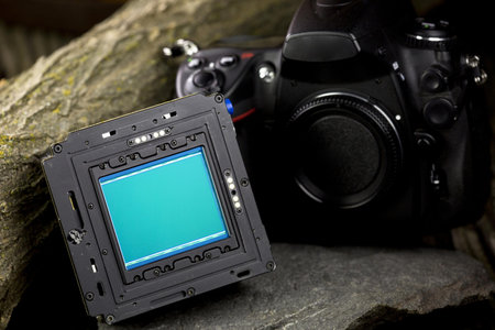Digital SLR camera with blue screen on a rock. Close up.