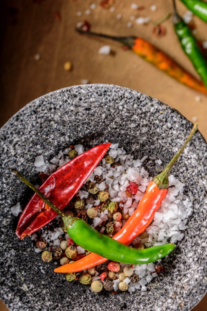 Hot chilli peppers and salt in a mortar on wooden background.の写真素材