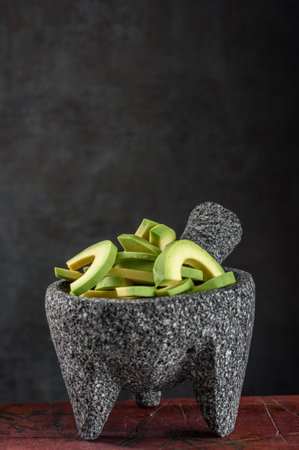 Avocado slices in granite mortar and pestle on dark background.の写真素材