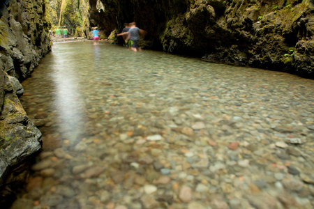 Mountain river flowing through a cave with people on the background.の写真素材