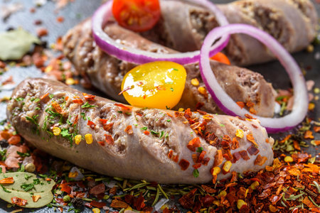 Raw pork sausages with spices and vegetables on a black backgroundの写真素材