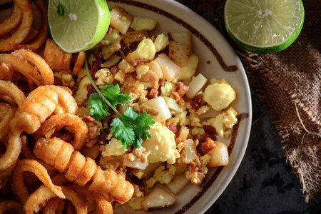 Fried squid rings with potato and onion served with lime and parsley