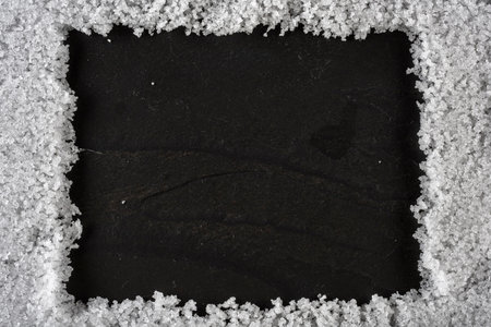 Frame made of snow on a black stone background. Top view.の写真素材