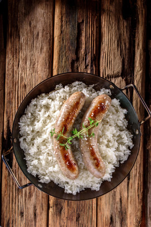 Grilled sausages with rice and thyme on a wooden backgroundの写真素材