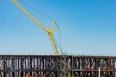 construction of a bridge over the river with a crane against the blue skyの写真素材