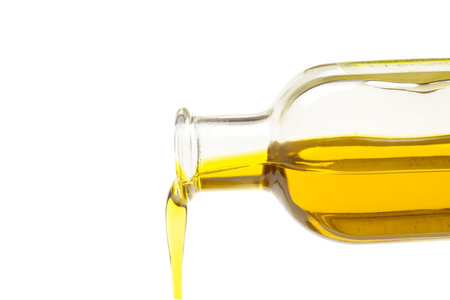 Olive oil pouring out of a bottle isolated on white background.の写真素材