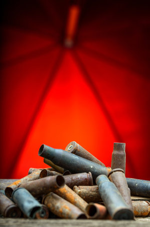 Old rusty bullets on a wooden table with a red umbrella in the background