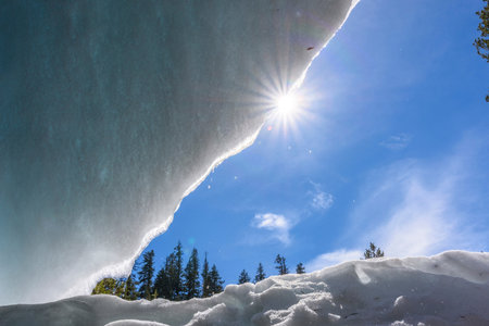 Winter landscape with snow covered trees and blue sky with sun rays.の写真素材