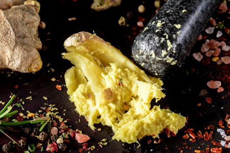 Mortar and pestle with garlic, ginger and spices on black backgroundの写真素材