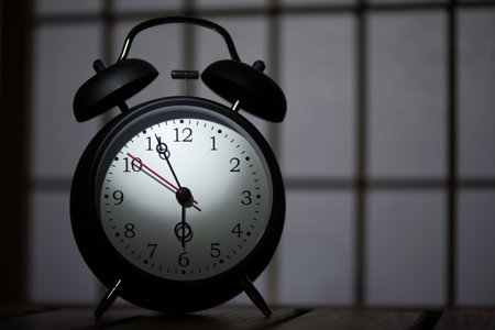 Black alarm clock on the wooden table in japanese room.