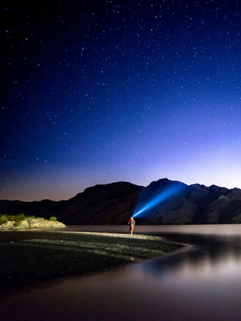 Night starry sky over lake with a man standing on the shoreの写真素材