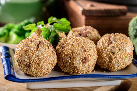 Deep-fried crab meat balls with sesame seeds on a wooden table.