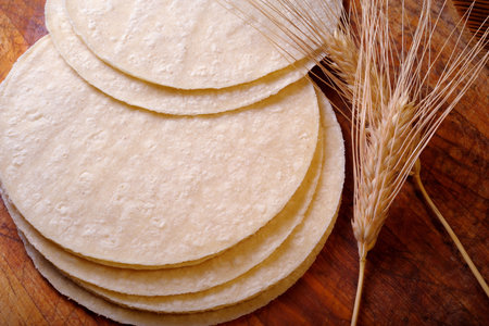 Wheat tortillas and ears of wheat on a wooden background.の写真素材
