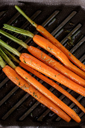 Bunch of fresh baby carrots on a cast-iron frying pan
