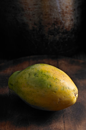Ripe papaya fruit on a wooden table. Dark background.の写真素材