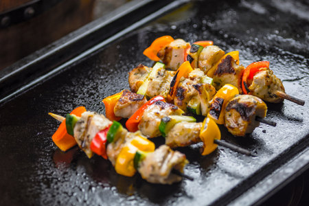 Grilled chicken skewers with bell pepper and onion on black plate