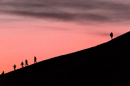 Silhouette of a group of people walking on the hill at sunset