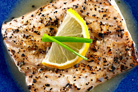 Grilled salmon fillet with lemon on blue plate. Top view.