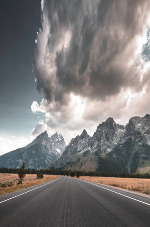Asphalt road in the mountains with dramatic sky and clouds, travel conceptの写真素材