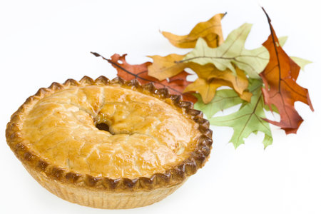 apple pie with autumn leaves on a white background, close-up