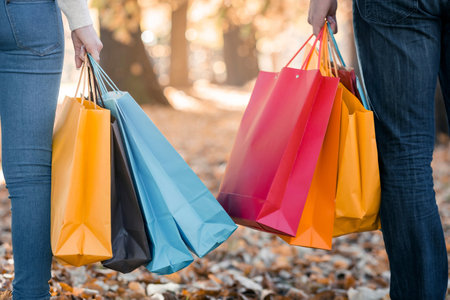 Close-up of couple holding shopping bags in the park on a sunny dayの写真素材