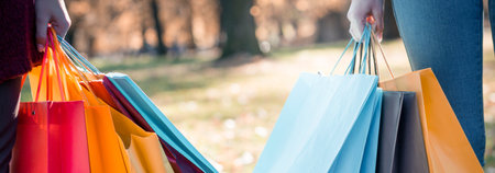 Close-up of a young woman holding shopping bags in the park.の写真素材